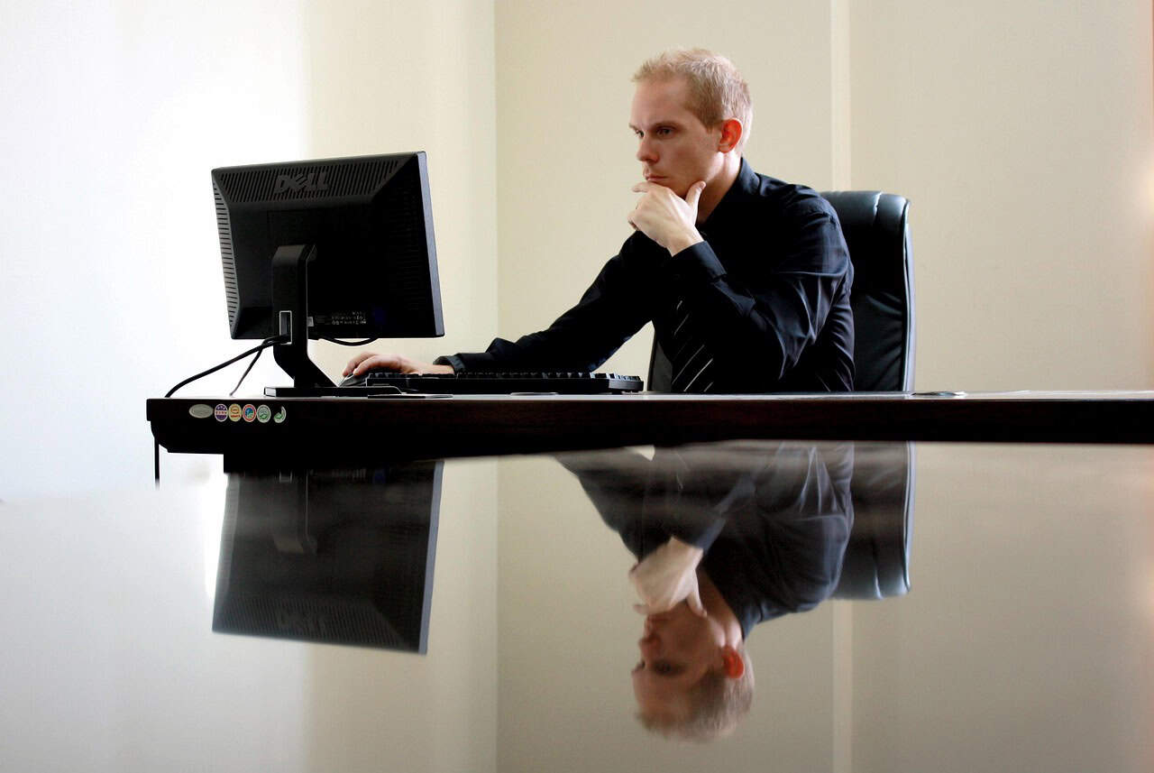 Image of a professional man working on a computer for live chat monitoring and customer support management.