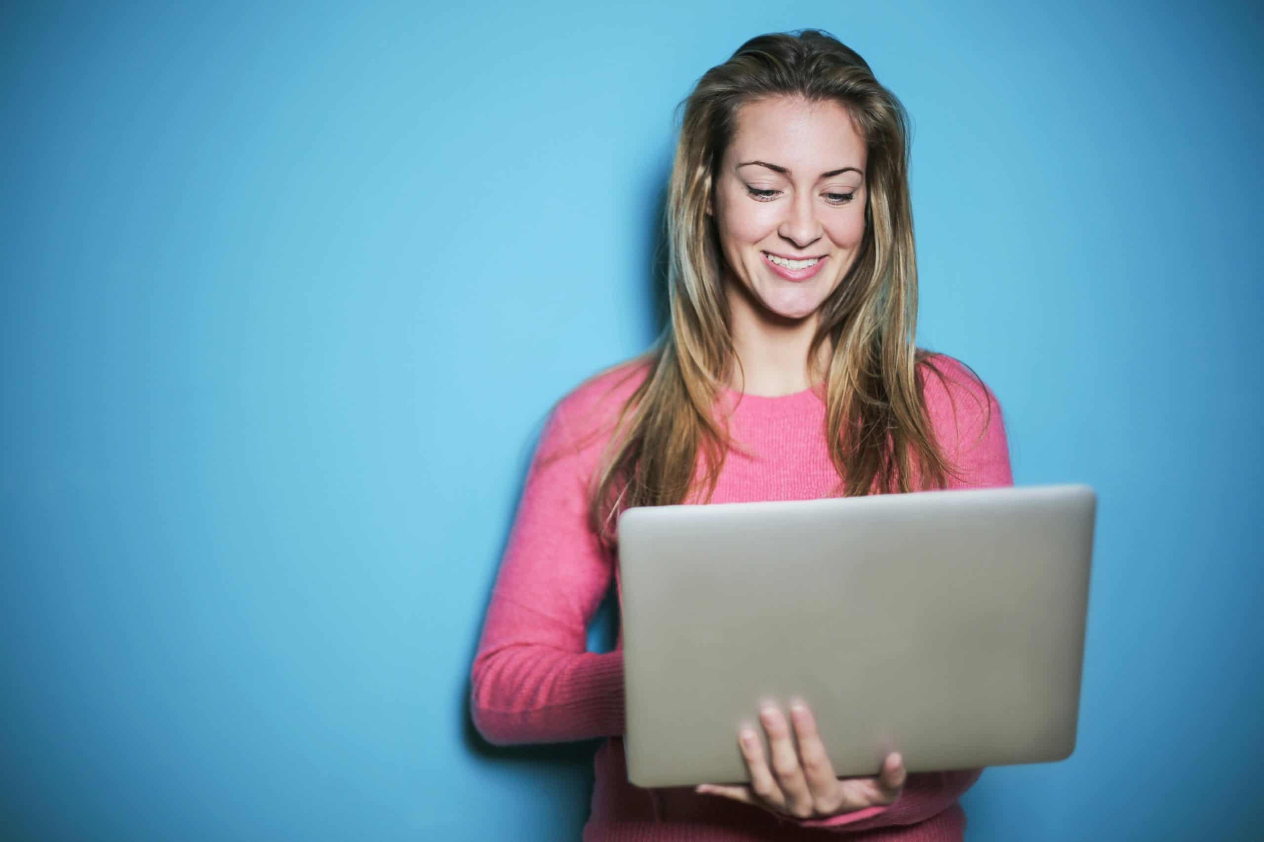 Woman using laptop for live chat customer support monitoring.