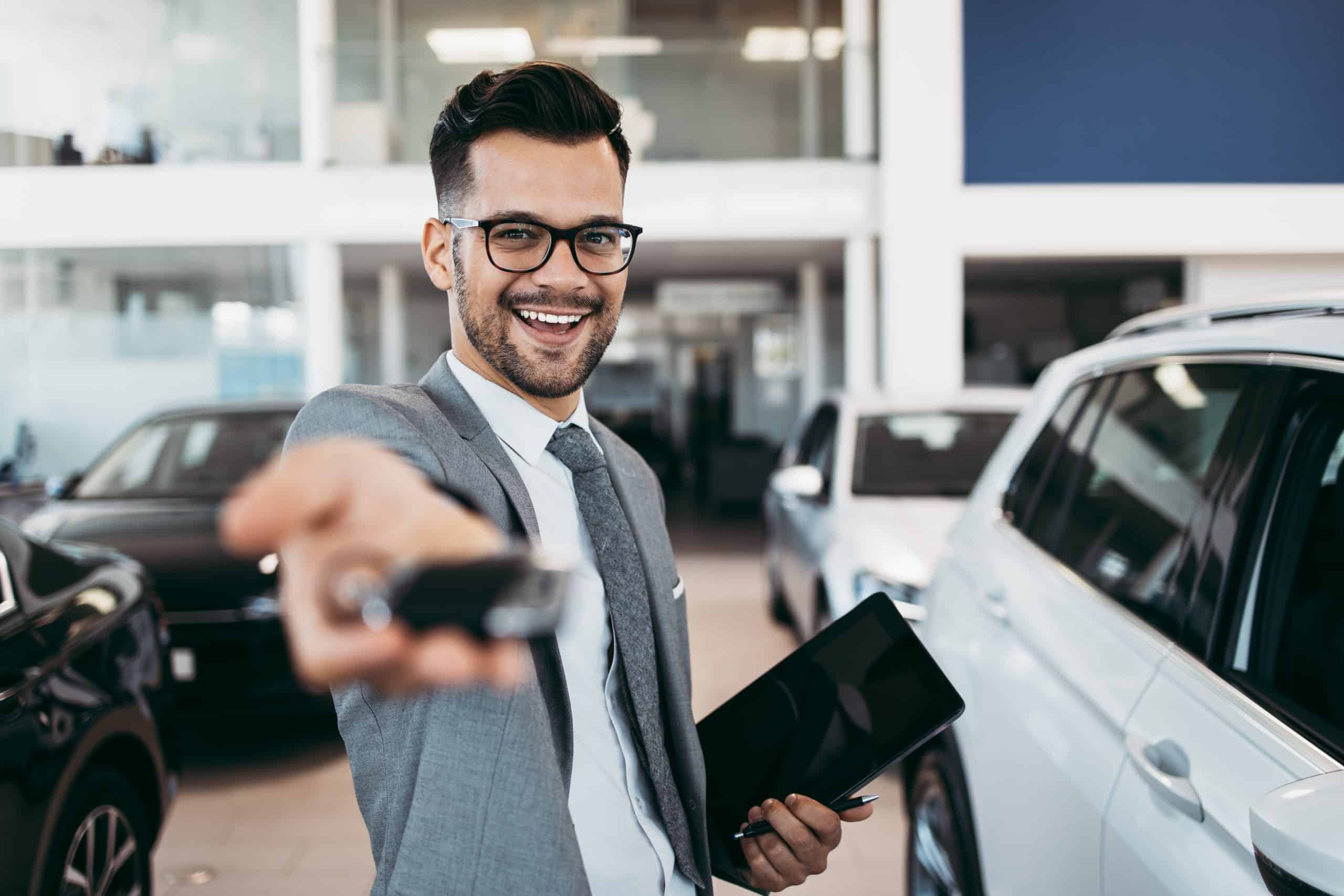 Customer service representative smiling with car keys inside a dealership, showcasing live chat support for automotive sales.