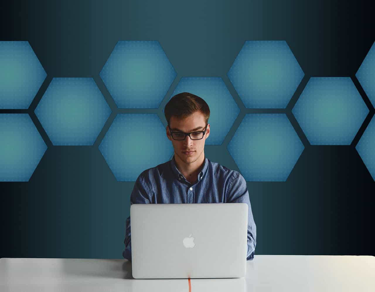 Young man analyzing live chat data on his laptop in a modern tech environment.