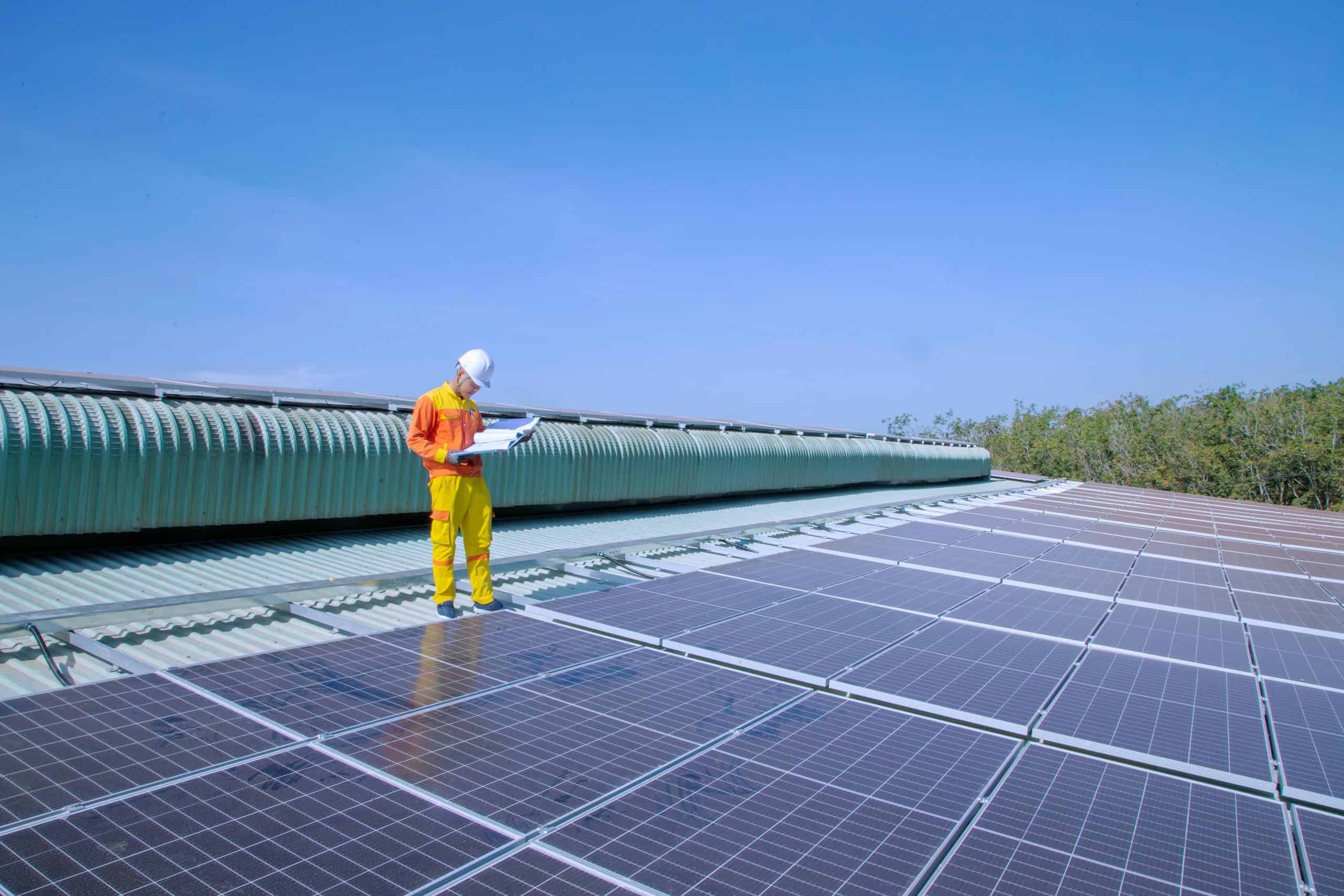 Image of technician inspecting solar panels on a roof for live chat monitoring.