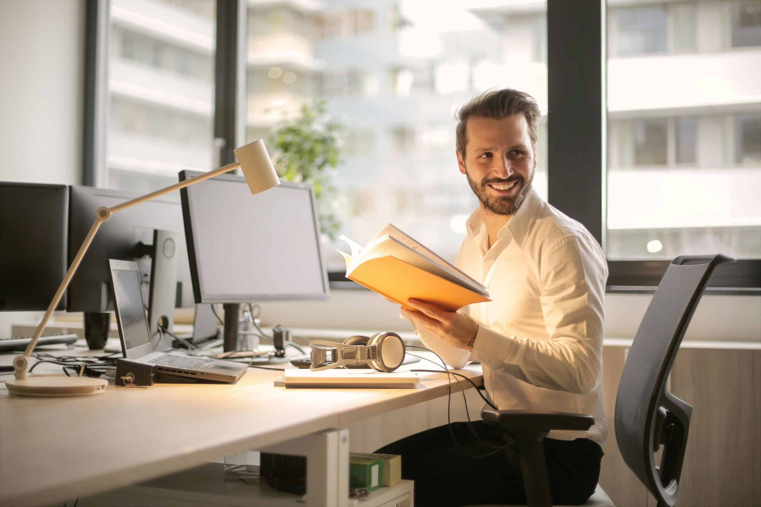 Young man working on live chat monitoring with multiple computer screens in modern office.