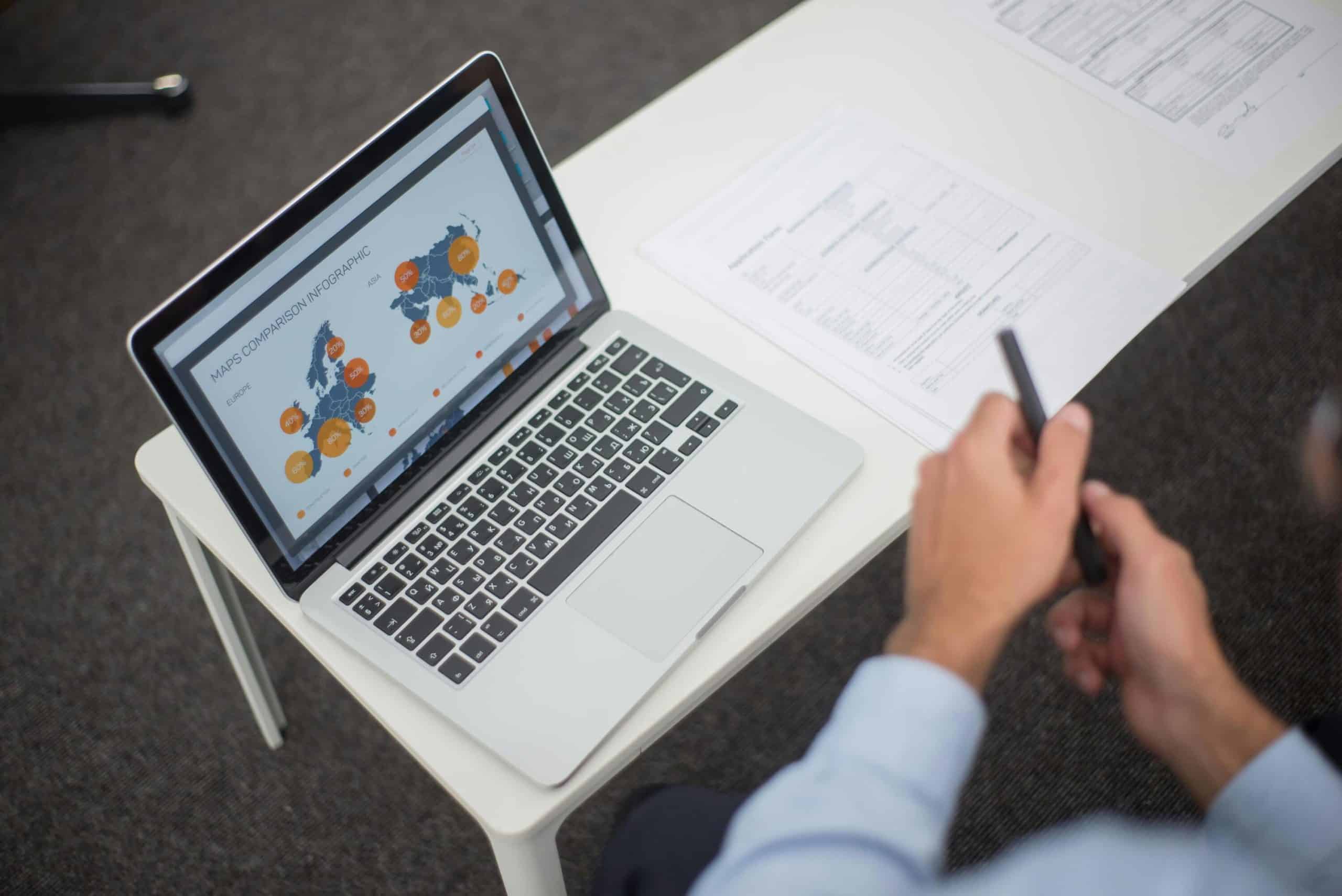 Business professional using smartphone with live chat monitoring on laptop screen.