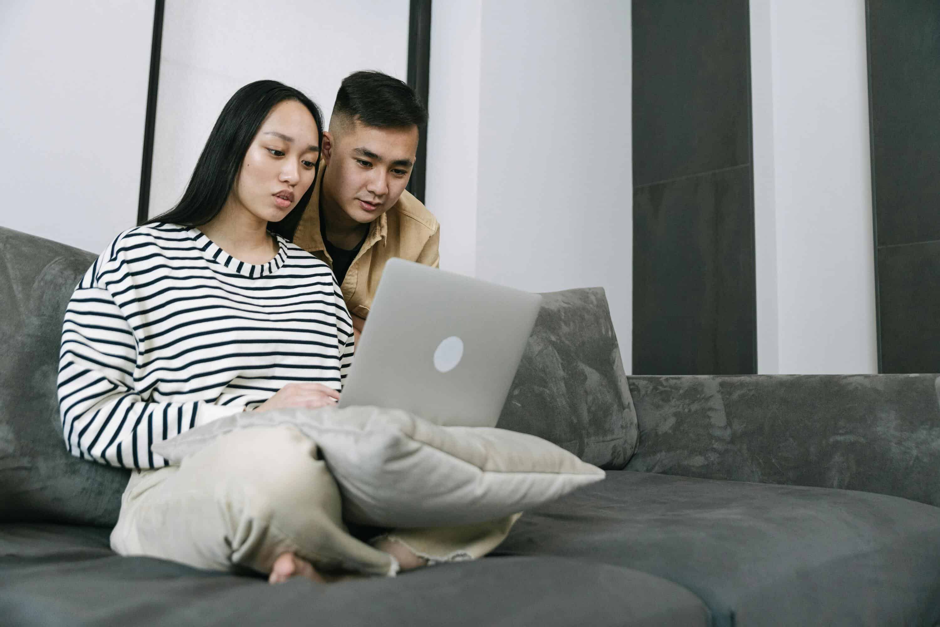 Two young professionals using a laptop for live chat monitoring and customer support.